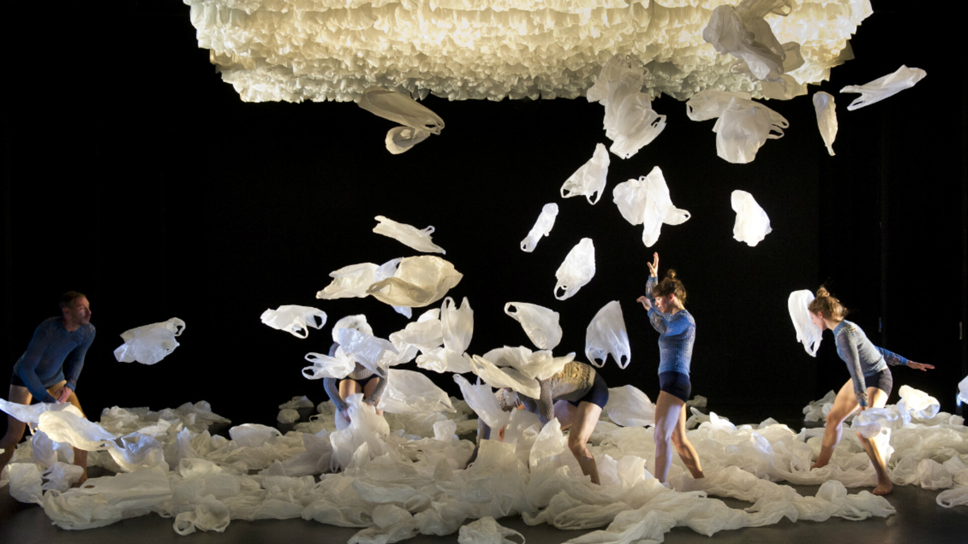Dancers throw plastic bags into the air.